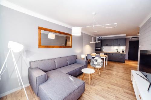 a living room and kitchen with a couch and a table at FARO Apartamenty Polanki Park z basenami in Kołobrzeg