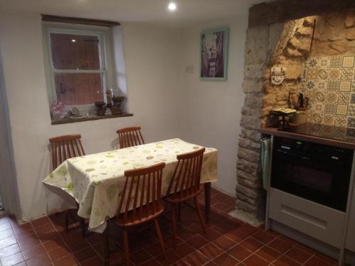 una cocina con una mesa con 4 sillas y una ventana en The Old Swan walkers cottage en Bath