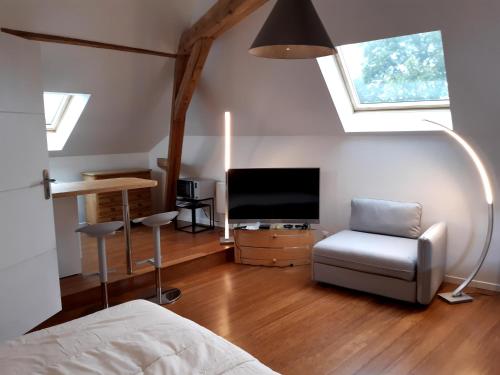 a bedroom with a bed and a tv and a chair at loft studio avec charme et authenticité in Altkirch