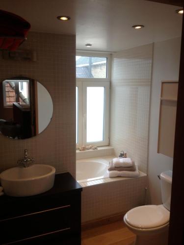 a bathroom with a tub and a sink and a toilet at De Zevende Hemel in Merendree