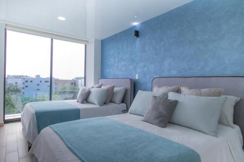 a bedroom with two beds and a blue wall at Macondo Quinta Avenida Residences in Playa del Carmen