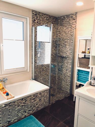 a bathroom with a tub and a glass shower at Hausboot Elandi in Bitterfeld