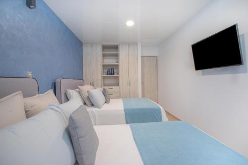 a bedroom with two beds and a flat screen tv at Macondo Quinta Avenida Residences in Playa del Carmen