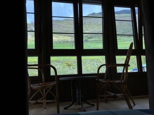 2 sillas y una mesa frente a una ventana en Valle del sol II en Pajares