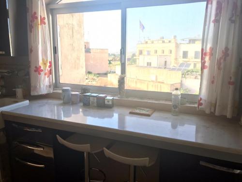 Hal Ghaxiak的住宿－Casa Montegri 1，厨房柜台设有窗户和2把凳子
