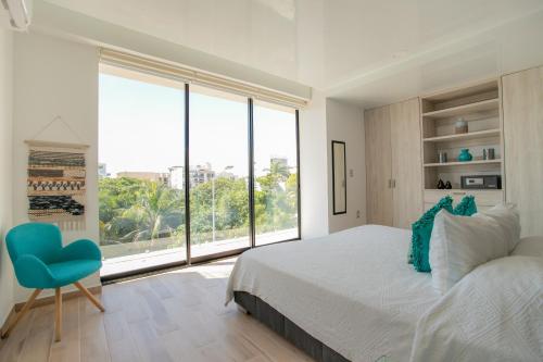 a bedroom with a bed and a large window at Macondo Quinta Avenida Residences in Playa del Carmen