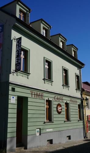 a green and white building with a sign on it at Time Cafe & Penzion in Příbram