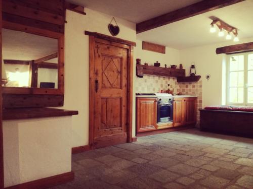 une cuisine avec des placards en bois et une porte ouverte dans l'établissement La Casetta di Lele e Schina, à Arvier