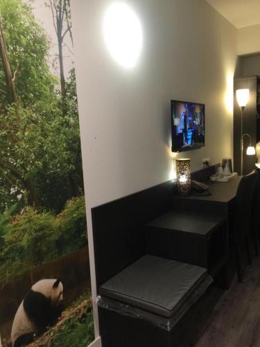 a room with a desk and a tv on a wall at cité impériale ye in Mettet