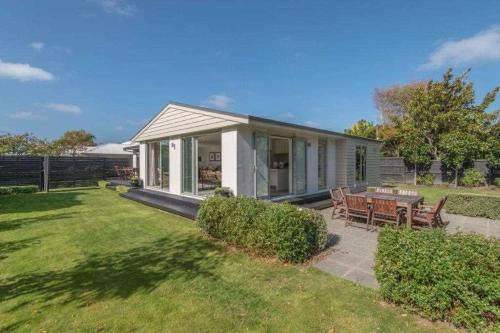 a small white house with a picnic table in a yard at Bed & Breakfast in the Heart of Fendalton in Christchurch