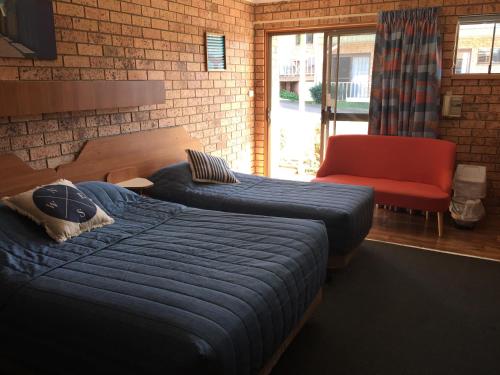 a bedroom with two beds and a red chair at Whale Fisher Motel in Eden