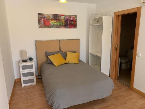 1 dormitorio con 1 cama con 2 almohadas amarillas en Apartamento de 1 dormitorio, Ático 4PAX en Alcorcón