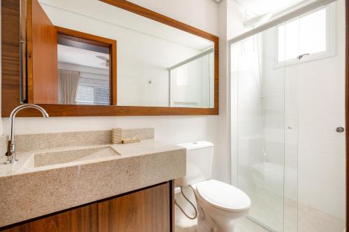 a bathroom with a sink and a toilet and a mirror at Pousada Residencial La Caracola in Florianópolis