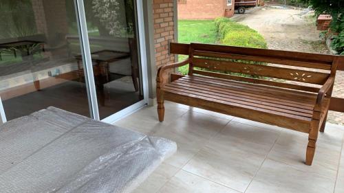 a wooden bench sitting in front of a window at Refúgio das Araucárias in Ibiúna
