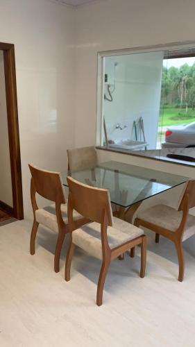 a glass dining table with two chairs and a mirror at Refúgio das Araucárias in Ibiúna