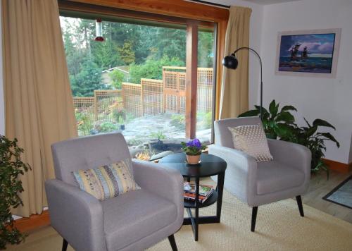 two chairs and a table in a living room with a window at Mossy Hill Suite in Salt Spring Island