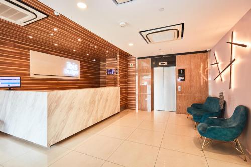 an office lobby with a reception desk and two chairs at ibis budget Singapore Crystal in Singapore