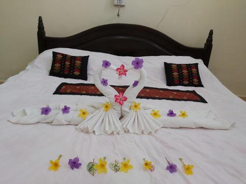 a bed with white sheets and flowers on it at Xuanmai Garden Resort in Pakse