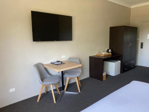 a room with a table and two chairs and a television at Jindy Inn in Jindabyne