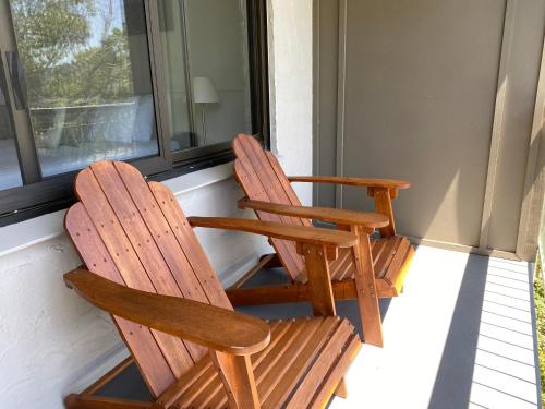 two wooden chairs sitting on a porch looking out a window at Jindy Inn in Jindabyne