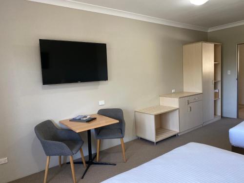 a hotel room with a desk and a tv on the wall at Jindy Inn in Jindabyne