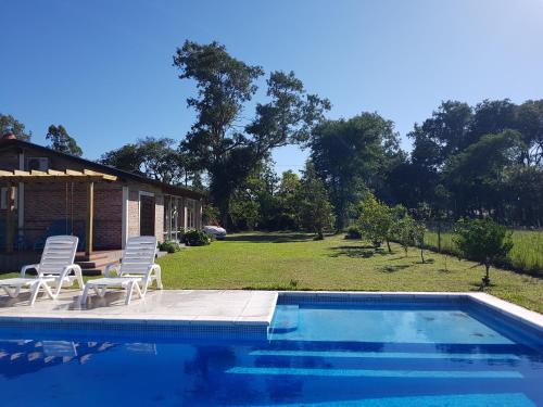 a swimming pool with two chairs and a house at Los Teros in Goya