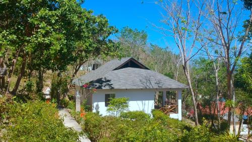 a small white house in the middle of trees at Chindonan Dive and Beach Resort in Coron