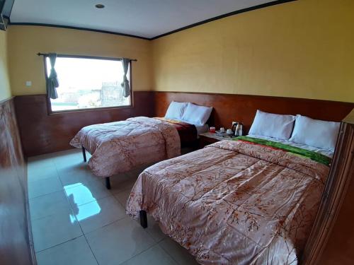 a hotel room with two beds and a window at Cemara Indah Hotel in Bromo