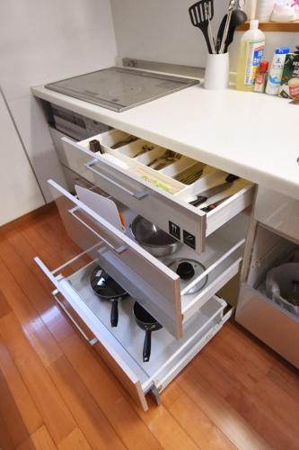 a kitchen counter with an open drawer with cooking utensils at 一棟貸し切り ゲストハウス Sai in Yasugi