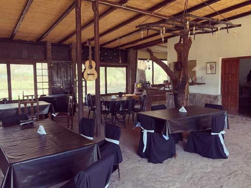 un comedor con mesas, sillas y una guitarra en Hotel Hacienda Casa Blanca en Tinogasta