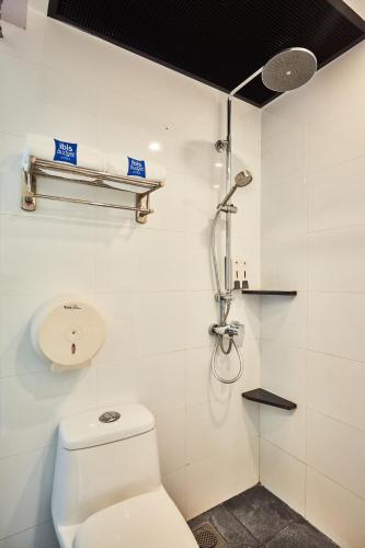 a white bathroom with a shower and a toilet at ibis budget Singapore Pearl in Singapore