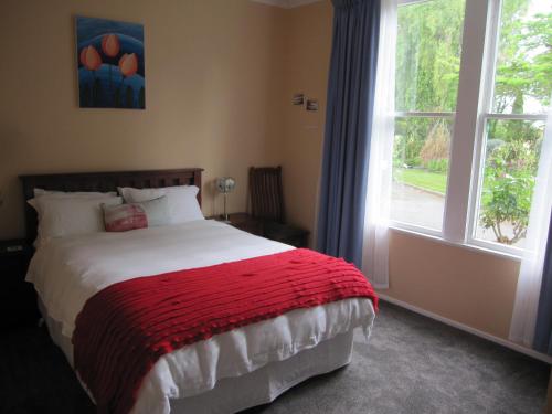 a bedroom with a bed with a red blanket and a window at Thyme Out Estate in Halcombe