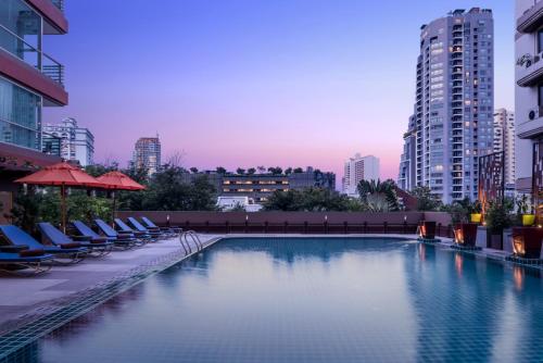 a swimming pool in a city with chairs and buildings at Adelphi Grande Sukhumvit in Bangkok
