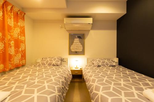 a bedroom with two beds and a lamp in it at Cross Bridge Ikebukuro in Tokyo