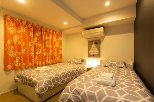 a bedroom with two beds and an orange curtain at Cross Bridge Ikebukuro in Tokyo