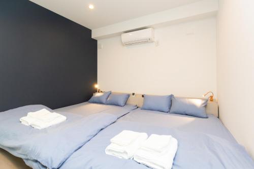a bed with blue sheets and white towels on it at Cross Bridge Ikebukuro in Tokyo