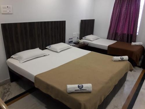 Dos camas en una habitación de hotel con toallas. en Hotel Ramco Residency A/c, en Kanchipuram