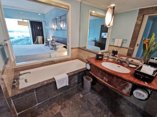 a bathroom with a large mirror and a tub and a bed at Thistle Johor Bahru in Johor Bahru