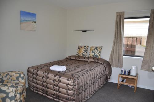 a bedroom with a bed and a chair and a window at Judges Pool Motel Turangi in Turangi