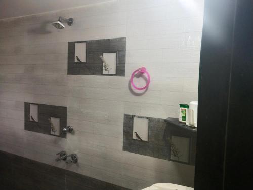 a bathroom with a shower with pictures on the wall at Hotel Rosary House in Malvan