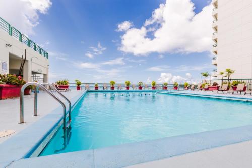 a swimming pool at a hotel with chairs and a building at Alupang Beach Tower in Tamuning