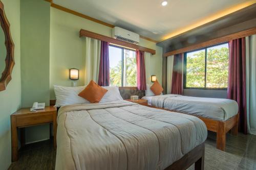 een hotelkamer met 2 bedden en 2 ramen bij Rawis Resort Hotel and Restaurant in Borongan