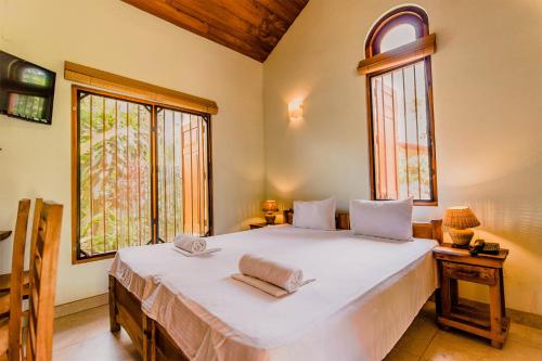 a bedroom with a large white bed with two windows at Villa Shade in Negombo