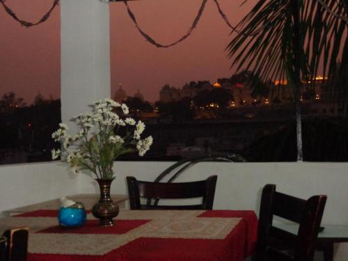 una mesa con un jarrón de flores en la parte superior de un balcón en Mohan Villa Guest House, en Udaipur
