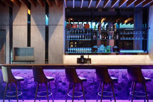 a bar with stools in front of a purple counter at ibis Kuala Lumpur City Centre in Kuala Lumpur