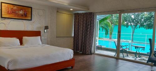 um quarto com uma cama e uma porta de vidro deslizante em Mrugavani Resort & Spa em Hyderabad