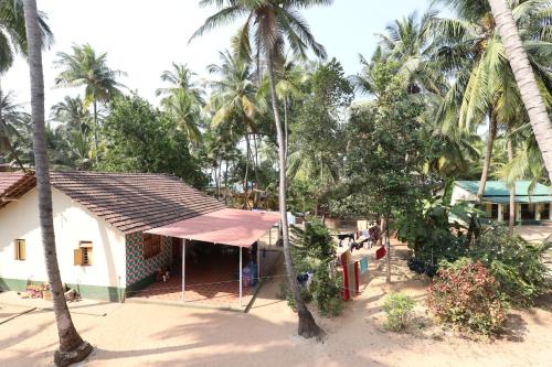 a house on the beach with palm trees at Hotel Rosary House in Malvan
