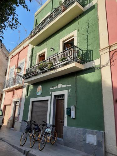 due biciclette parcheggiate fuori da un edificio verde di La Pita Guesthouse a Almería