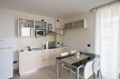 a kitchen with a table and a kitchen with white cabinets at Residence Aprilia in Grado