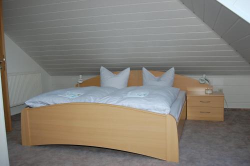 a bedroom with a wooden bed with white sheets and pillows at Landgasthof "Am Park" in Crottendorf